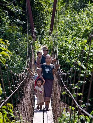 A family crosses a suspension bridge built by The Gibbon Experience.