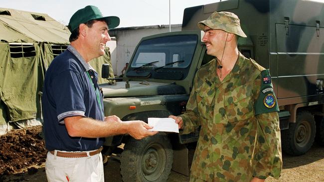 Townsville Bulletin reporter, Tony Raggatt, hands over a message from home to a soldier in Suai. Images from East Timor back in 1999 and 2000.