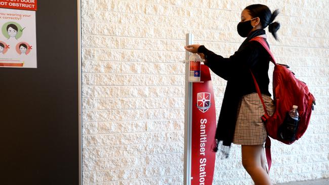A student at Caroline Chisholm Catholic College in Braybrook sanitises her hands as she arrives at school. Picture: NCA NewsWire / Andrew Henshaw