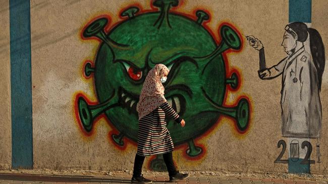 A Palestinian woman walks past a coronavirus-inspired mural in Gaza City. Picture: AFP