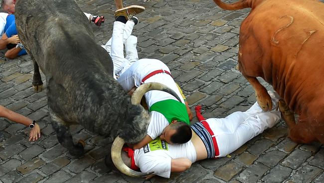 What’s brave about this? Participants fall next to Cebada Gago fighting bulls on the third day of the San Fermin bull run festival in Pamplona. Picture: AFP/Ander Gillena