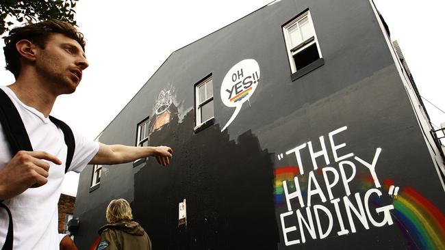 Local residents react to a mural that has been painted over with black paint in Newtown, Sydney, November 17, 2017. The mural, created by street artist Scott Marsh, depicted former prime minister Tony Abbott and Cardinal George Pell involved in a sex act celebrating the same-sex marriage survey 'yes' result. (AAP Image/Danny Casey) NO ARCHIVING