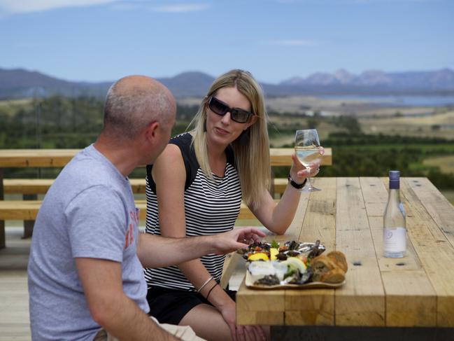 Guests sit out on the deck and take in the panoramic views of the majestic Hazards and Freycinet Peninsula at the Devil's Corner Cellar Door. Picture: Tourism Tasmania/Pete Harmsen.