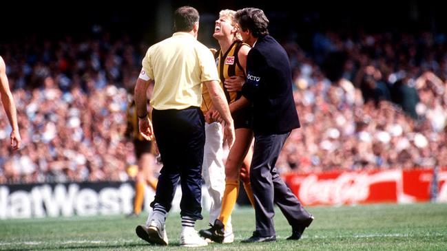 Dermott Brereton leaves the field after being cleaned up by Mark Yeates.