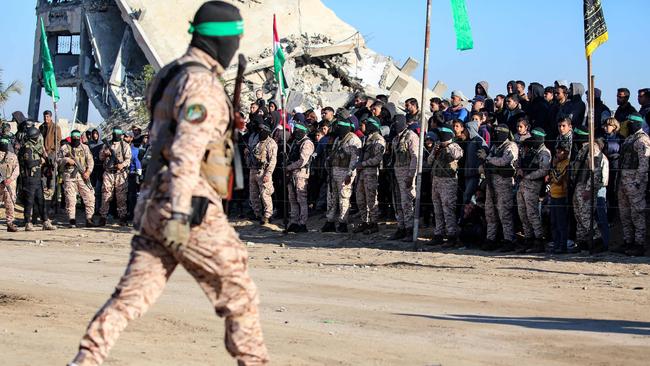 People watch from behind a human chain formed by Palestinian Hamas fighters as they secure an area before handing over the three Israeli hostages to a Red Cross team in Khan Younis in the southern Gaza Strip. Picture: AFP