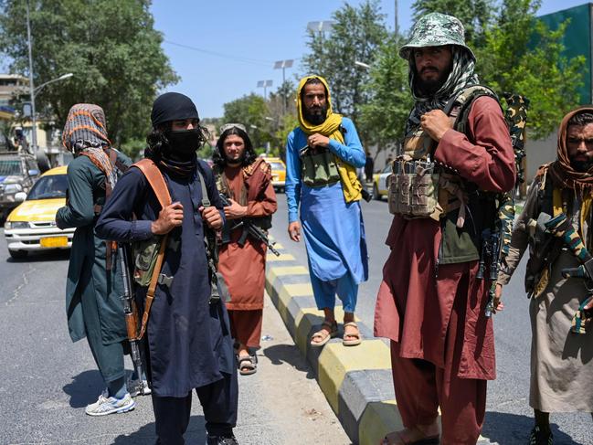 TOPSHOT - Taliban fighters stand guard along a street near the Zanbaq Square in Kabul on August 16, 2021, after a stunningly swift end to Afghanistan's 20-year war, as thousands of people mobbed the city's airport trying to flee the group's feared hardline brand of Islamist rule. (Photo by Wakil Kohsar / AFP)