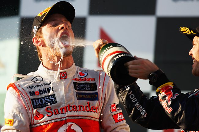 Second place getter Sebastien Vettel (right) helps Button celebrate the win on the podium. (Photo by Mark Thompson/Getty Images)