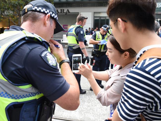 Witnesses try to help police trace the driver’s route from Flinders Street Station to Bourke Street Mall with photos on their phones. Picture: Lawrence Pinder