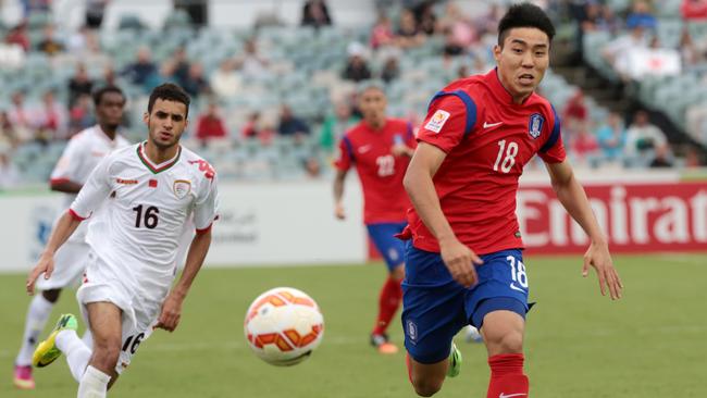 South Korea's Lee Jeonghyep, right, chases the ball as Oman's Ali Sulaiman Al Busaidi looks on.