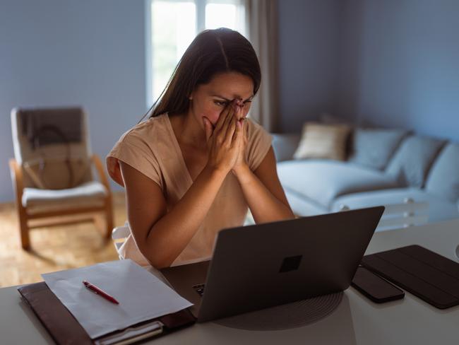 Female victim of financial fraud, looking anxious. She is at her home, discovering financial fraud; scams, scammer generic