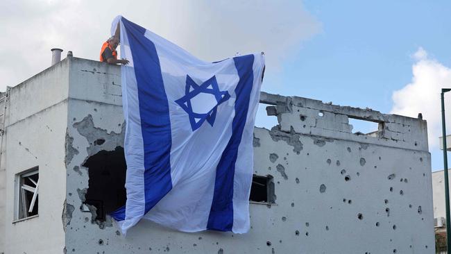 People hang a giant Israeli flag from the roof of a damaged building in Kiryat Bialik in the Haifa district of Israel, following a reported strike by Hezbollah. Picture: AFP