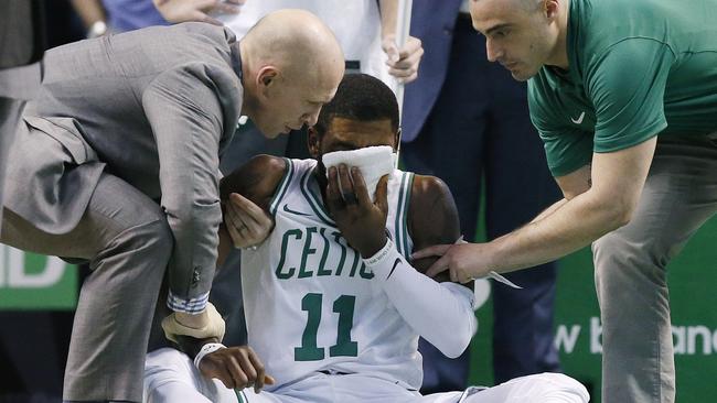 Team personnel assist Boston Celtics' Kyrie Irving.