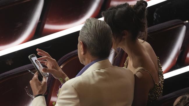 Jeff Goldblum and wife Shauna Robertson checked out their red carpet photos as they waited for the Oscars to start. Picture: AP Photo/Chris Pizzello