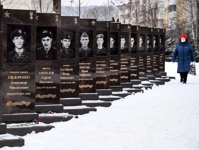 TOPSHOT - A woman walks past a monument to the soldiers killed in action during wars in Afghanistan and Chechnya in the village of Shebekino outside Belgorod, a few kilometres from Ukrainian border, on January 27, 2021. - The border with Ukraine, the scene of a major geopolitical crisis, is just a stone's throw away, but the Russians see no war on the horizon. In fact, far from the tense diplomatic exchanges between Moscow and Washington, which blame each other for the tensions around Ukraine, this border region seems to be asleep. (Photo by Alexander NEMENOV / AFP)