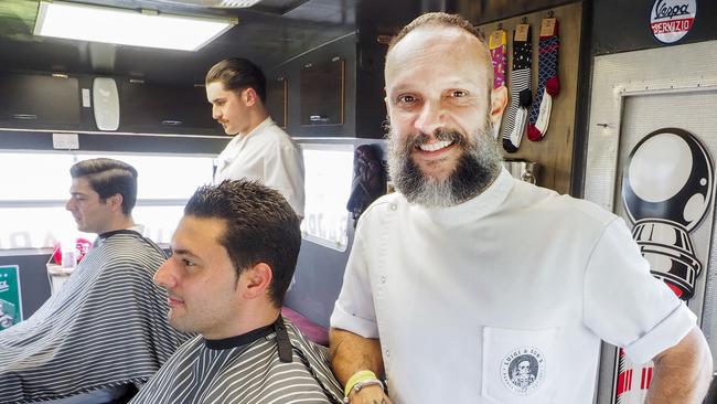 Luigi and Sons Mobile Barber proprietor Joey D'Adderio with customer Paolo Saltafossa at the Gold Coast Turf Club. Picture: Tim Marsden