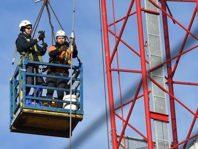 Construction workers are seen dismantling a damaged crane in Richmond, Melbourne, Wednesday, July 25, 2018. Wild winds have impacted the structural integrity of the construction crane, which resulted in the evacuation of nearby residents and the closure of Bridge road. (AAP Image/James Ross) NO ARCHIVING