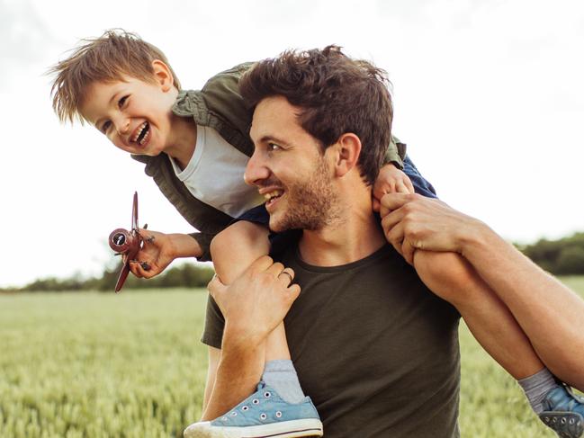 Photo of a cheerful little boy, being supported to be a pilot, by his father who is holding him on shoulders