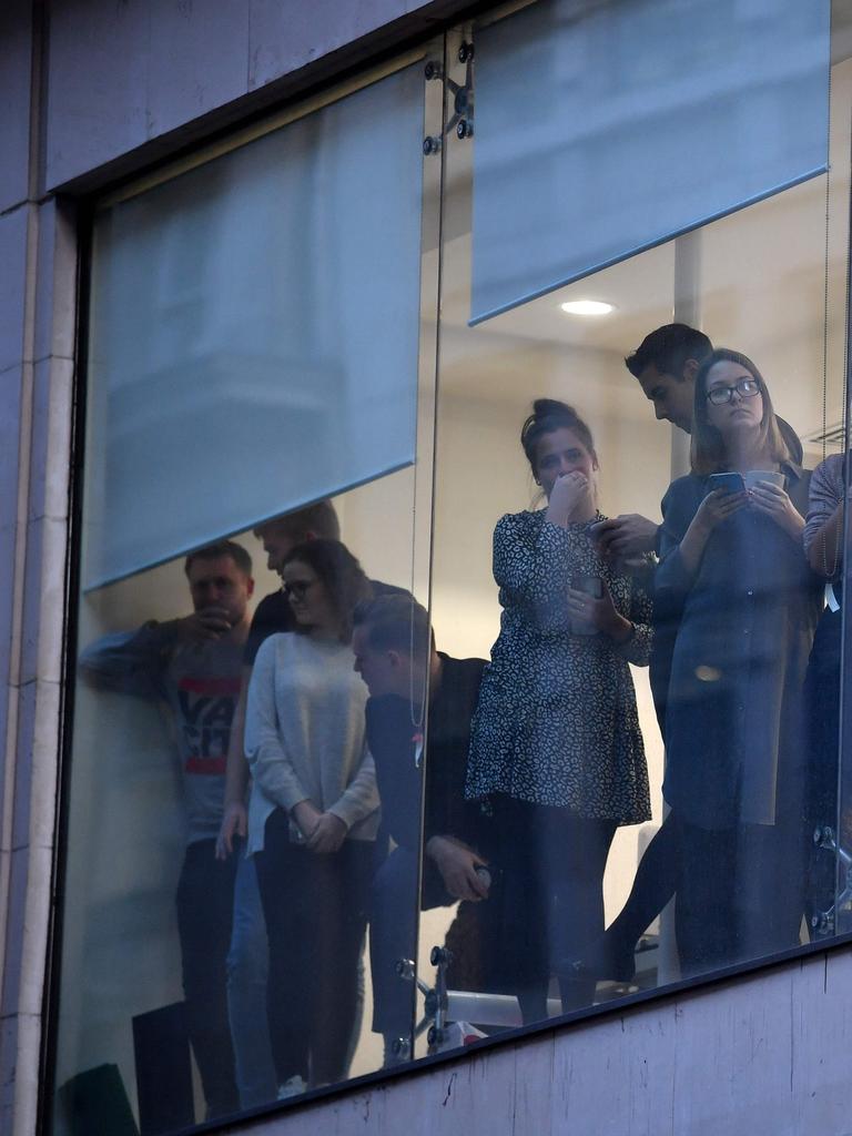 Office workers peer out of the windows of Leadenhall Market. Picture: Ben STANSALL.