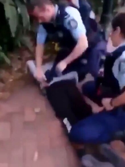 The boy is then handcuffed while another officer holds down his legs. Source: Monica Kelly