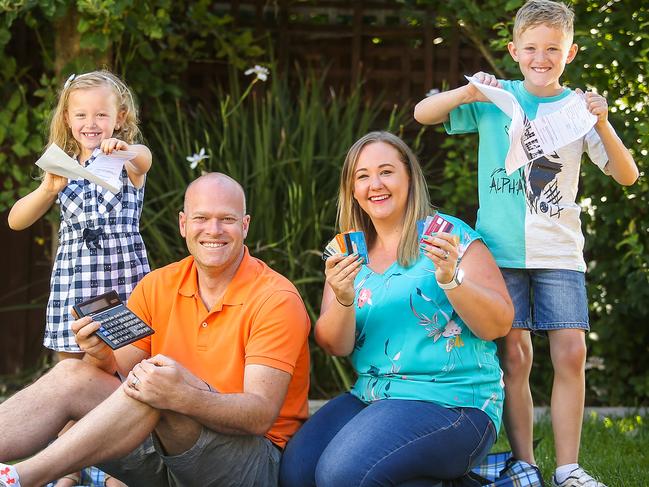 Kylie and Richard Don and their kids, Lachlan (8) and Ruby (6,) pose with credit cards and bank statements, as they plan for a debt free 2019. Picture: Martin Keep