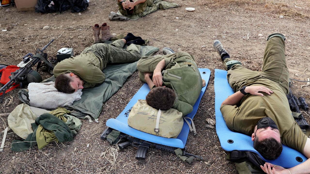 Israeli soldiers holding a position rest in a field near the kibbutz Beeri in southern Israel on October 14, 2023, close to the spot where 270 revellers were gunned down or burnt in their cars by Hamas. Picture: Thomas COEX / AFP