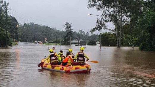 A pregnant mother and her young diabetic son are ferried across flooded Moggill Rd.