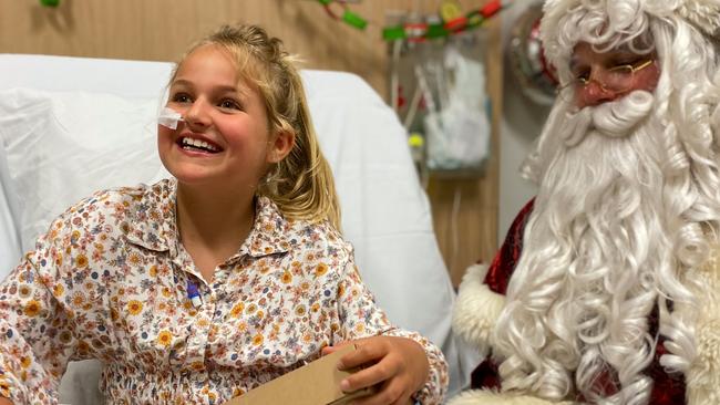 Indee Rose Gower, 8, with Santa after opening her favourite dinosaur egg at Gold Coast University Hospital. Picture: Supplied.