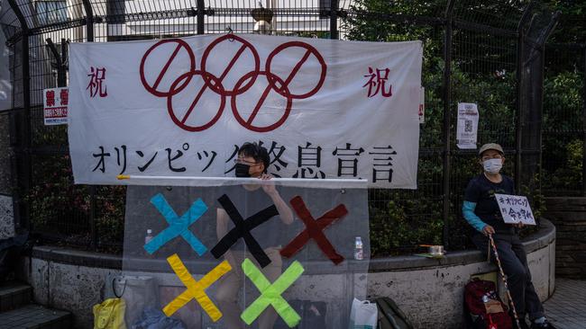 A protester holds a banner as he sits beside another during a demonstration against the forthcoming Tokyo Games. Picture: Getty