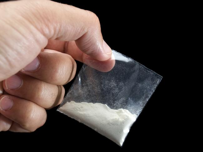 Generic photo of cocaine. Dealer is holding drug bag in his hand on a black background. Picture: iStock