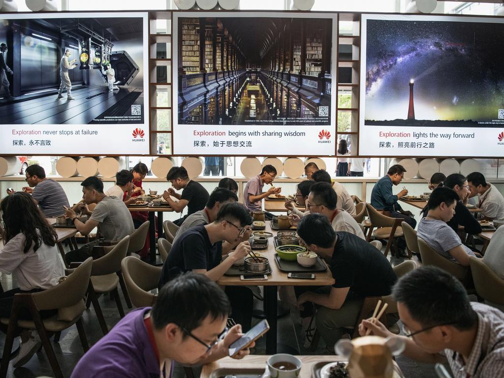 Corporate messages are beamed at Huawei workers eating lunch. Picture: Getty