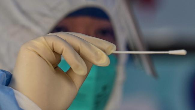 A health worker conducts a swab test for the Covid-19 coronavirus at a residential compound in Shanghai on March 18, 2022. (Photo by Hector RETAMAL / AFP)