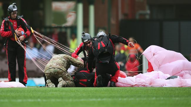 A member of the Australian Army Red Beret is attended to after crahing on landing during an ANZAC ceremony ahead of AFL match Sydney Swans v West Coast Eagles at the SCG. Picture. Phil Hillyard