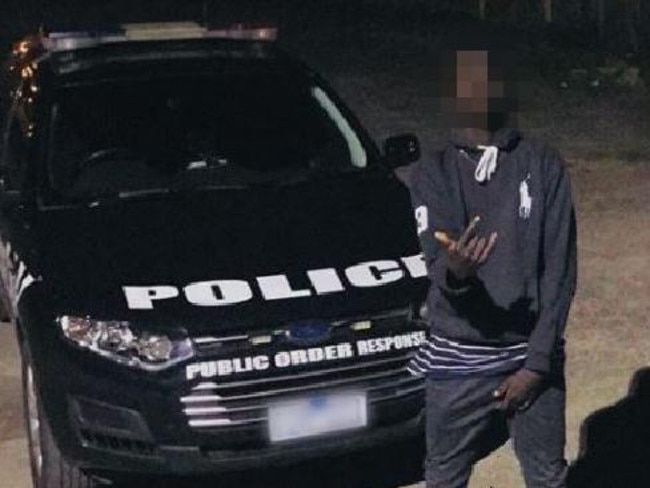 An African youth posing with a Victoria Police car. Pictures were posted on social media to taunt police.