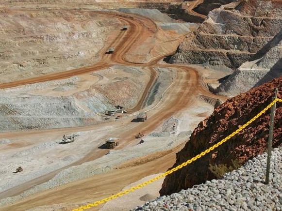 Visitors cast shadows as they look out over part of the main pit of Newcrest Mining Ltd.'s Telfer Mine in the Pilbara region of Western Australia Thursday, July 28, 2005. The mine, which was officially opened today, will be Australia's largest gold and copper producer. Photographer: Will Burgess/Bloomberg News