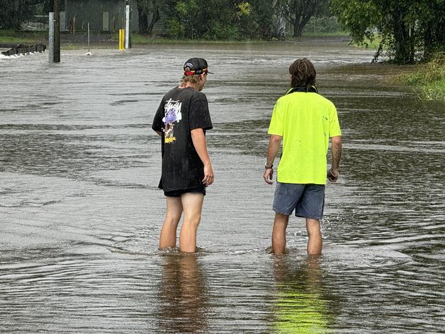 Locals testing the depths of the water over the service road flooded by Martins Creek at  Kunda Park. Picture - Mark Furler.