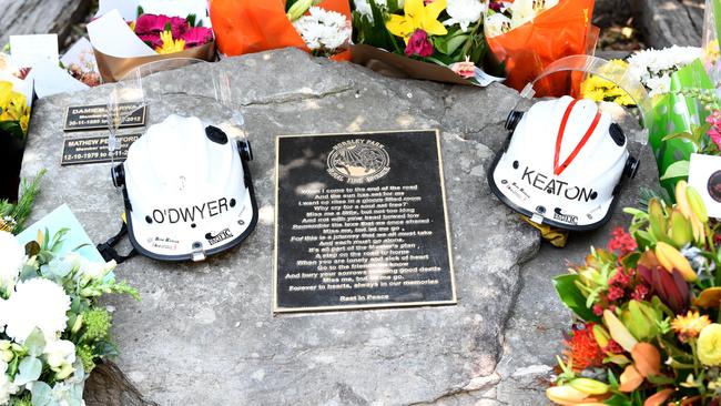 Flowers and the helmets of volunteer firefighters Andrew O'Dwyer and Geoffrey Keaton at a memorial at the Horsley Park Rural Fire Brigad. Picture: AAP Image/Bianca De Marchi