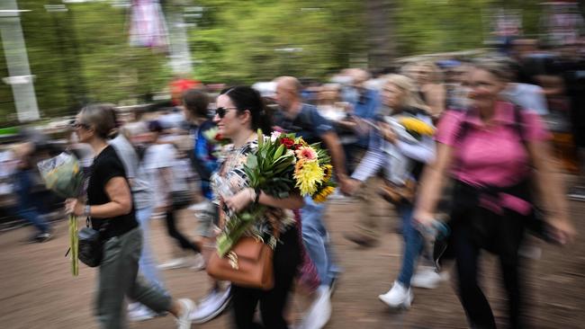 A woman holding a bouquet among a crowd of well-wishers near Buckingham Palace on Sunday. Flowers will be banned from the Queen’s lying in state in Westminster Hall. Picture: AFP