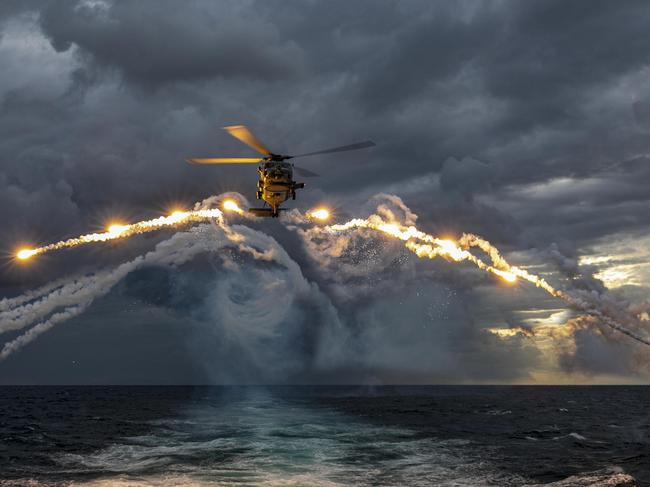 An MH-60R Seahawk helicopter embarked on HMAS Parramatta deploys Counter Measure Dispense System flares during a training flight conducted on a deployment through South East Asia. Picture: Department of Defence