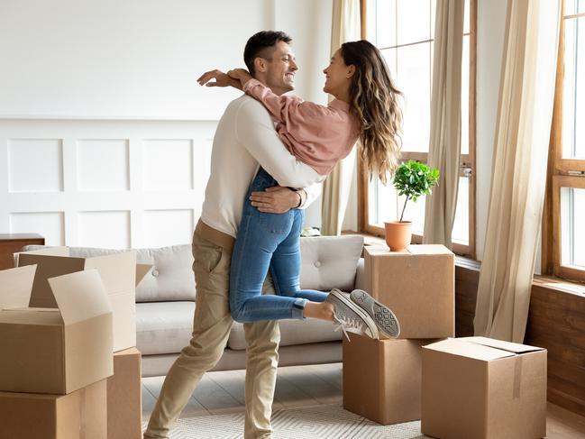 Happy young husband lifting excited wife celebrating moving day with cardboard boxes, proud overjoyed family couple first time home buyers renters owners having fun enjoy relocation, mortgage concept istock image