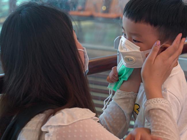 SINGAPORE, SINGAPORE - JANUARY 25: A woman wearing a mask helps her son put on his mask at Changi Airport on January 25, 2020 in Singapore. Yesterday Singapore confirmed its third case of the deadly coronavirus which emerged last month in the city of Wuhan in China. (Photo by Ore Huiying/Getty Images)