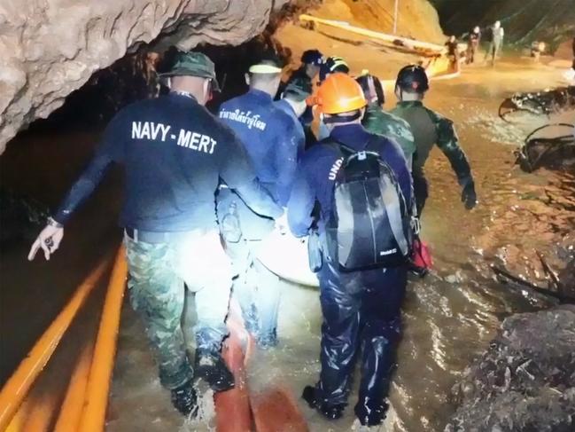 Rescue personnel coming out of the Tham Luang cave system with one of the boys. Picture: AFP