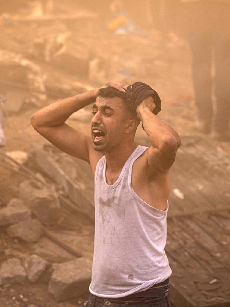 A Palestinian man reacts as others check the rubble of a building in Khan Yunis. Picture: Mahmud Hams / AFP