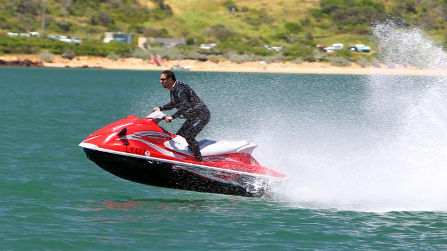 A man on a jet ski makes a seemingly intentional turn towards a pod of dolphins in Port Phillip Bay, near Mornington.