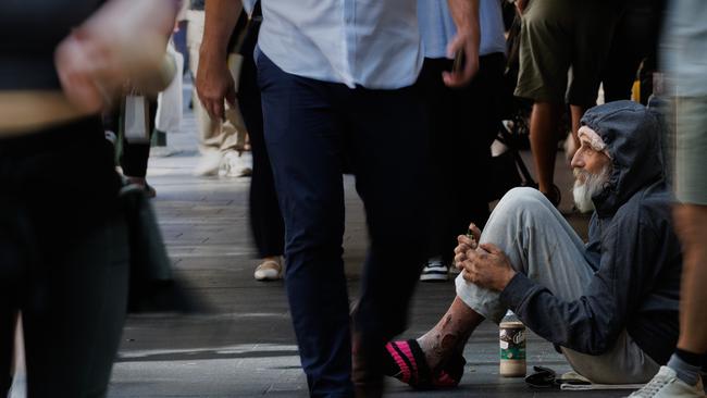 Shoppers pass an elderly homeless man with sores on his legs outside a supermarket in Sydney’s Pitt Street Mall. The number of Australians at risk of homelessness has surged by more than 60 per cent in the last eight years to three million. Picture: NewsWire/Max Mason-Hubers