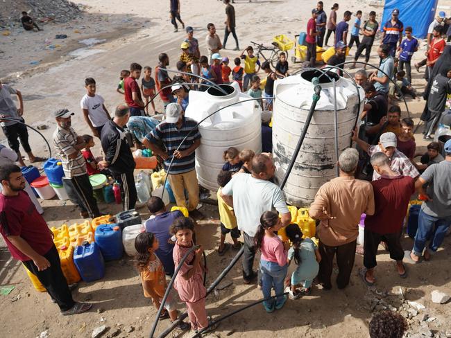 Palestinians gather around two large water tanks as they siphon water into smaller containers in a residential district of the southern Gaza Strip city of Khan Yunis on July 5. Photo: AFP.