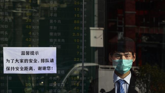 A Chinese man wears a protective mask as he waits for customers in a takeaway restaurant in Beijing. Picture: Getty Images