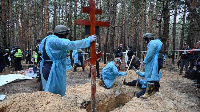 Officials dig a grave in a forest on the outskirts of Izyum. Picture: Sergey Bobok/ AFP.