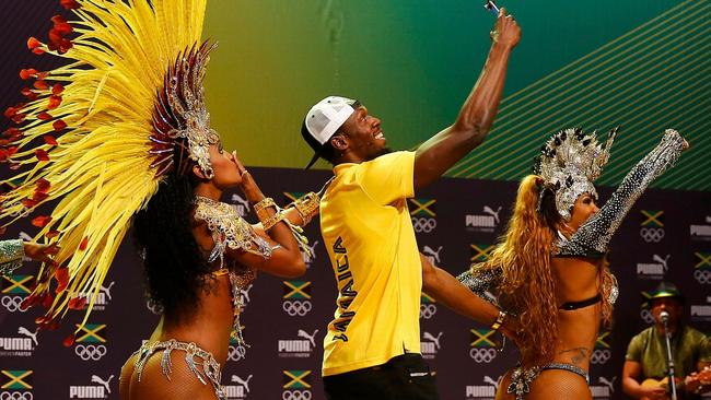 Bolt takes a selfie with a dancer during the press conference.