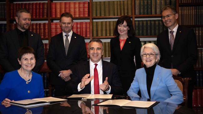 (Front L to R) Chancellor of the University of SA Pauline Carr, Premier Peter Malinauskas, Chancellor of the University of Adelaide Catherine Branson sign a historic agreement for the creation of a new university for South Australia. Picture: Emma Brasier