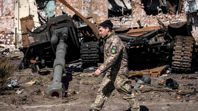 A Ukrainian serviceman walks between damaged Russian army tank and rubble of a destroyed building in the northeastern city of Trostianets, Picture: AFP